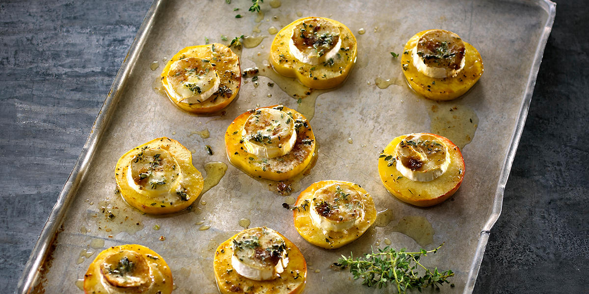 Chèvre chaud med eple og timian, servert på stekebrett i metall, med frisk timian rundt.