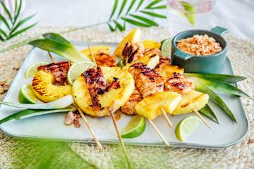 Grillet ananas med kylling og bacon på fat med peanøttdipp i en skål på siden