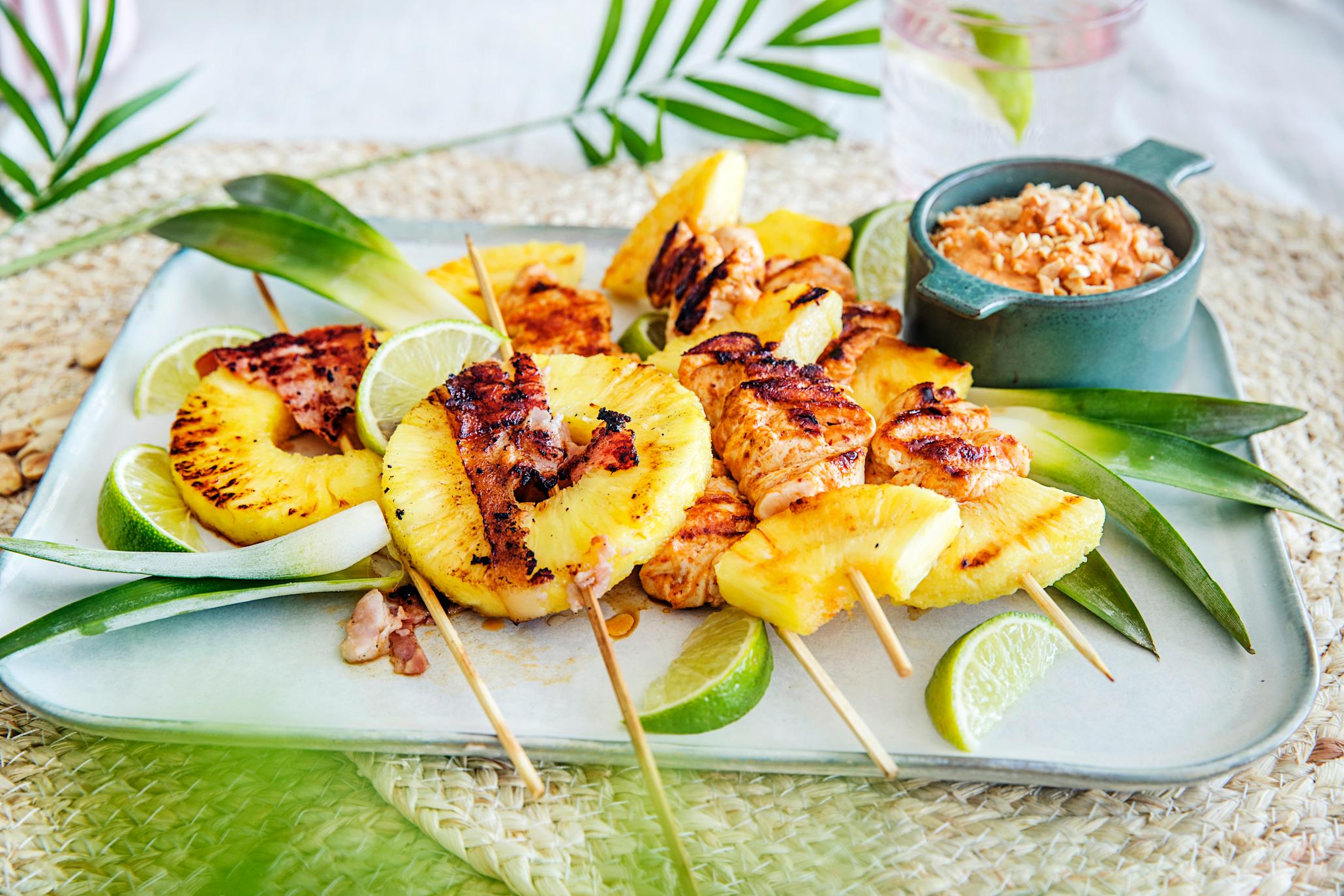 Grillet ananas med kylling og bacon på fat med peanøttdipp i en skål på siden