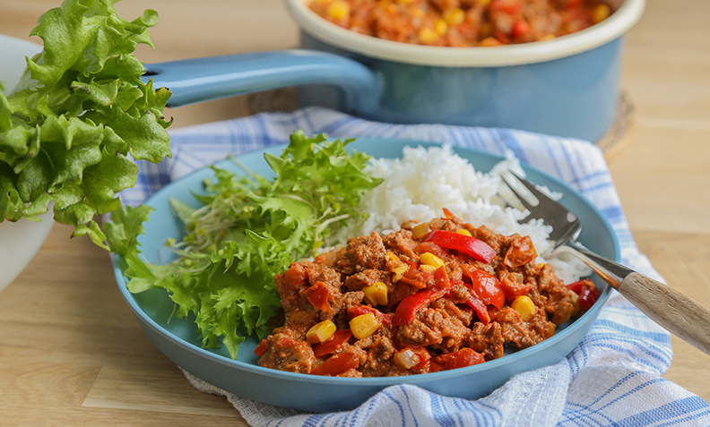 Tacogryte med hjemmelaget tacokrydder, servert med ris og salat på blå tallerken.