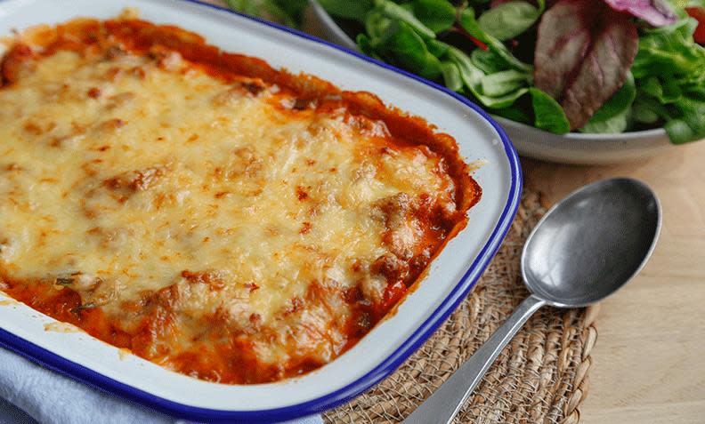 Kjøttdeiggrateng a la moussaka, gratinert kjøttdeig i tomatsaus, servert i ildfast form med blå kant. Salat på siden.