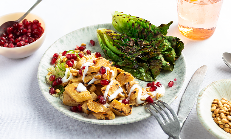Veganfilet med couscous og granateple servert på en dyp tallerken med kniv og gaffel