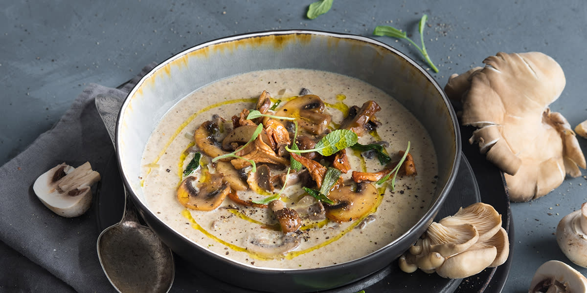 Herlig soppsuppe med salvie, servert i grå skål på grå linserviett. Diverse sopp og frisk salvie rundt skålen.