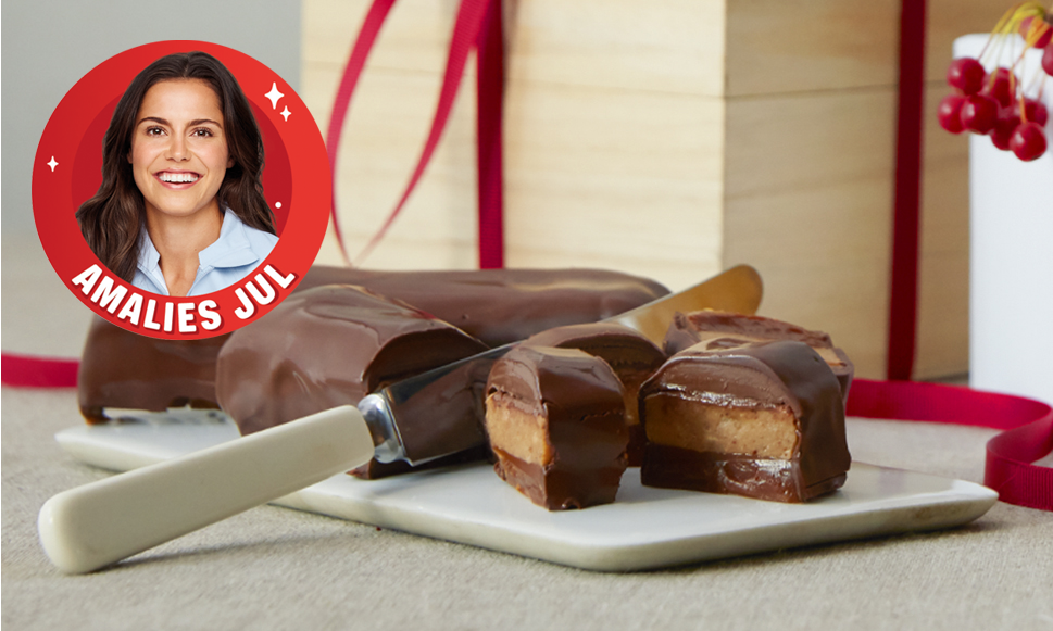 Hjemmelaget snickers skåret i biter og servert på hvit skjærefjøl. Bilde av Amalie Iuel på rød sticker øverst til venstre.