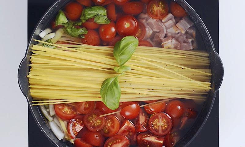 One pot pasta - kjele med ingredienser sett ovenfra. Kjelen inneholder spaghetti, tomater, løk, bacon og ferske urter.