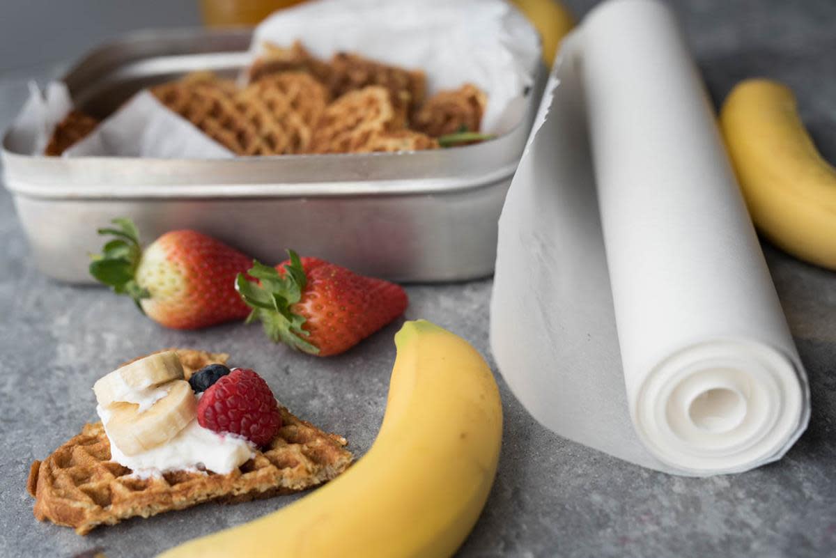 Bananvafler med havre ligger i matpakke, med bananer og ferske jordbær. Ett hjerte ligger ved siden av, med yoghurt, bær og skiver av banan.