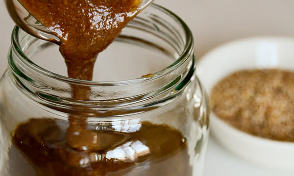 Hjemmelaget tahini som helles på glass. Lys skål med sesamfrø i bakgrunnen.