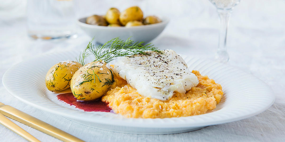 Juletorsk med verdens beste rotmos, dillpoteter og rødvinssaus servert på hvit tallerken på middagsbord med hvit duk og gullbestikk. Skål med dillpoteter i bakgrunnen.