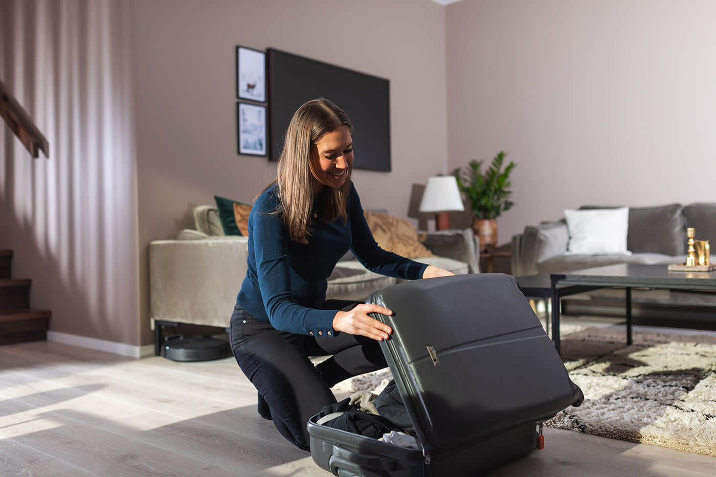 Kvinne pakker koffert på stuegulvet