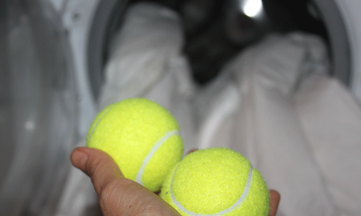 To tennisballer på vei inn i vaskemaskinen sammen med dundyne