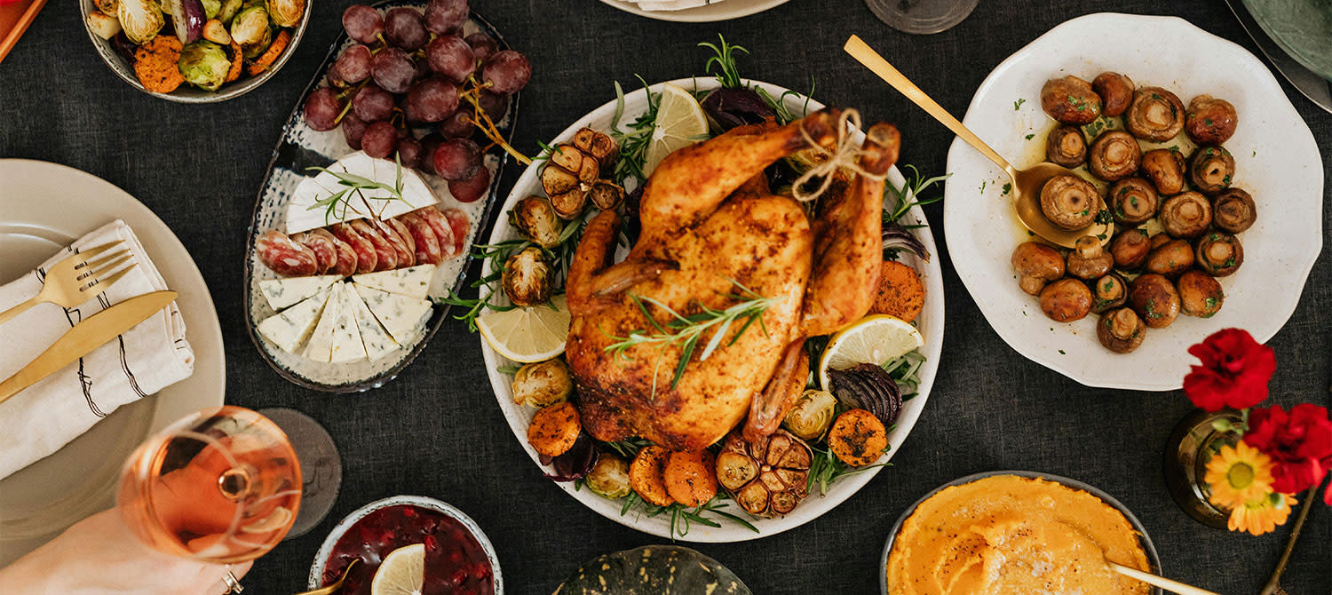 Bord dekket til Thanksgiving med en kalkun i midten, omgitt av andre retter til Thanksgiving.