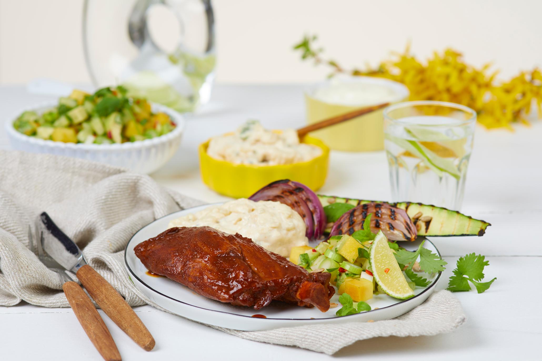 Pigwings BBQ med mango- og avokadosalat på hvit tallerken med potetsalat og grillede grønnsaker
