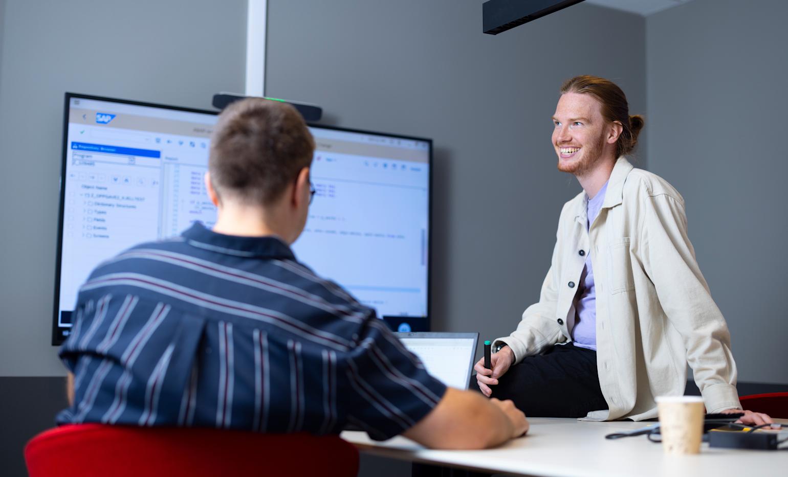 mann sitter smilende foran skjerm