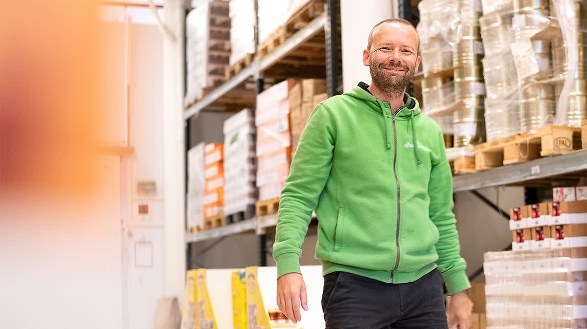 En smilende mann i grønn hettegenser kommer mot kamera