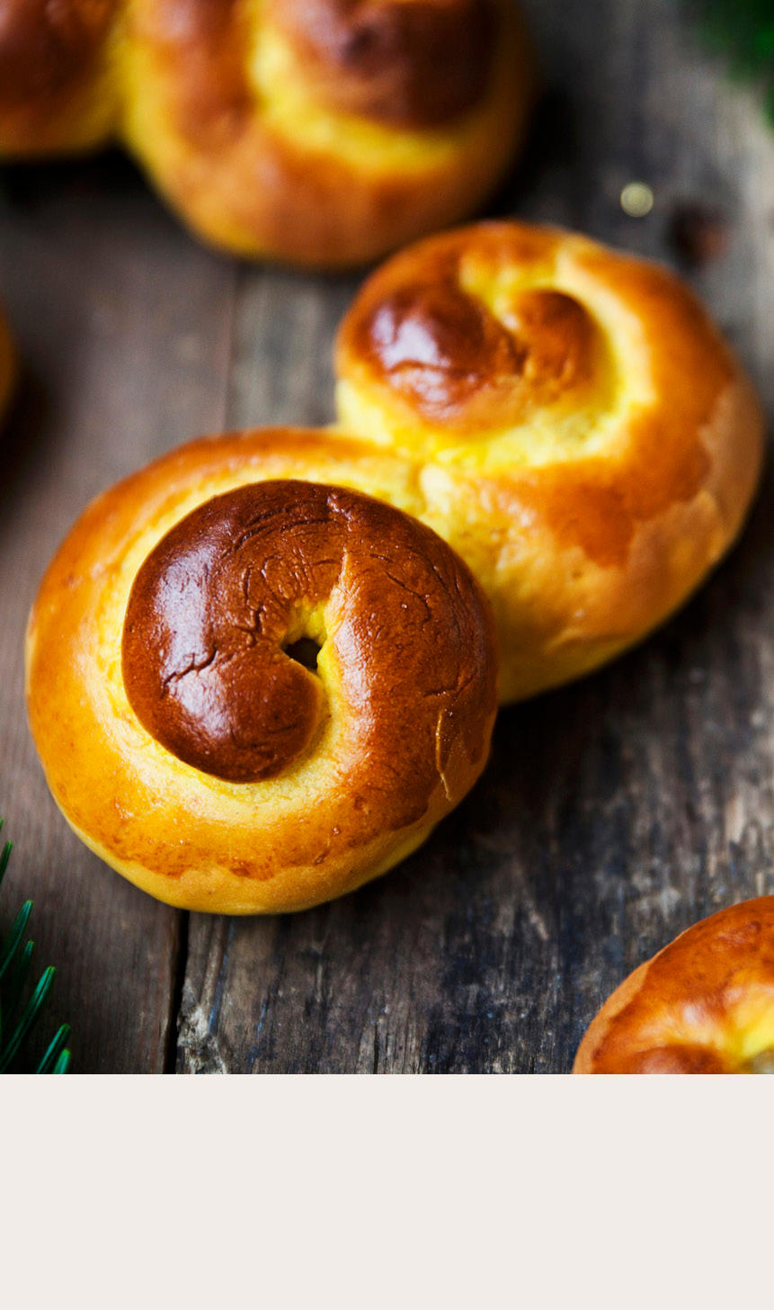 Lussekatter med granbar øverst og beige bakgrunn nederst