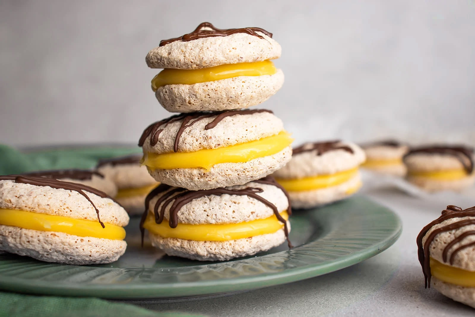 Gule bomber med nøttebunn og gul krem pyntet med mørk sjokolade og stablet i tårn på grønn asjett.