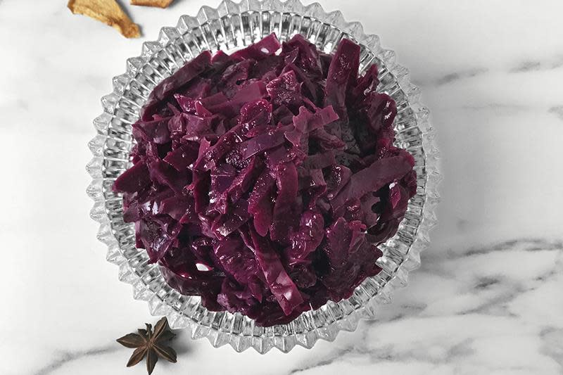 Krystallskål med hjemmelaget rødkål på hvit marmorbakgrunn. Stjerneanis ved siden av.