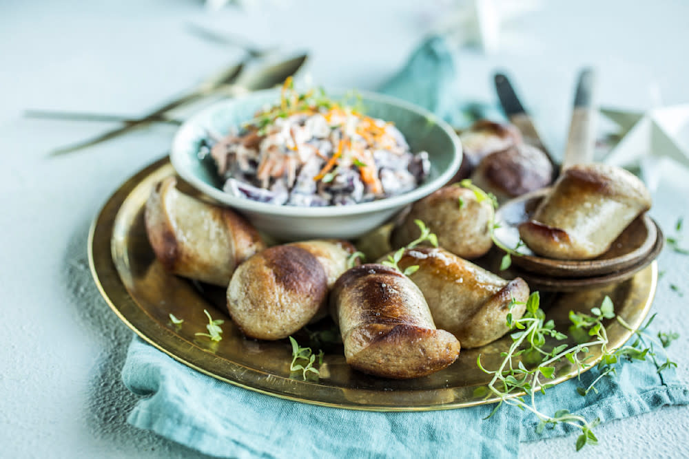Pannestekt julepølse med rødkålslaw servert på gullfarget tallerken med et dryss frisk timian på toppen.