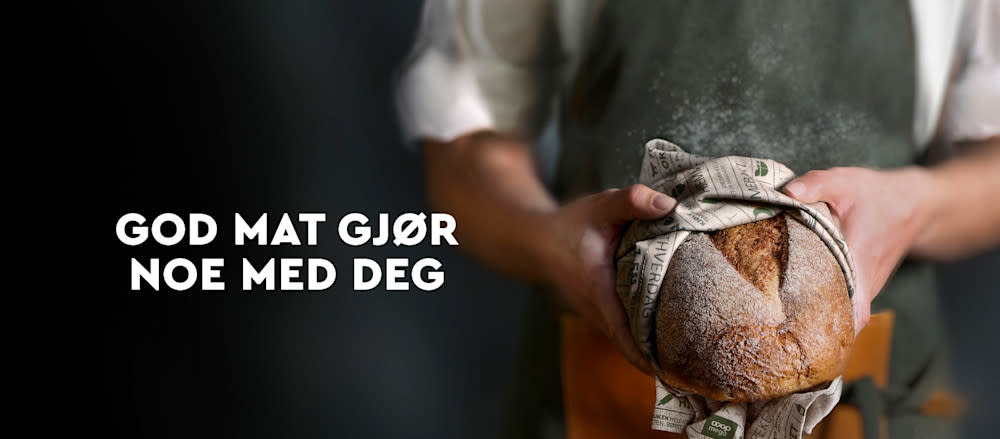 Armer strekker frem et nybakt brød kledd i Coop Mega kjøkkenhåndkle. Teksten God mat gjør noe med deg ved siden av.