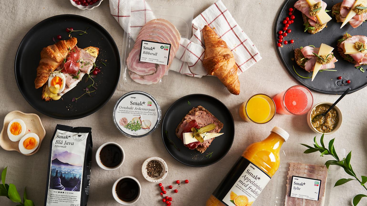 Et utvalg Smak* julepålegg servert på snitter på dekket bord til julelunsj med Blå Java kaffe, appelsinjuice og kokte egg.