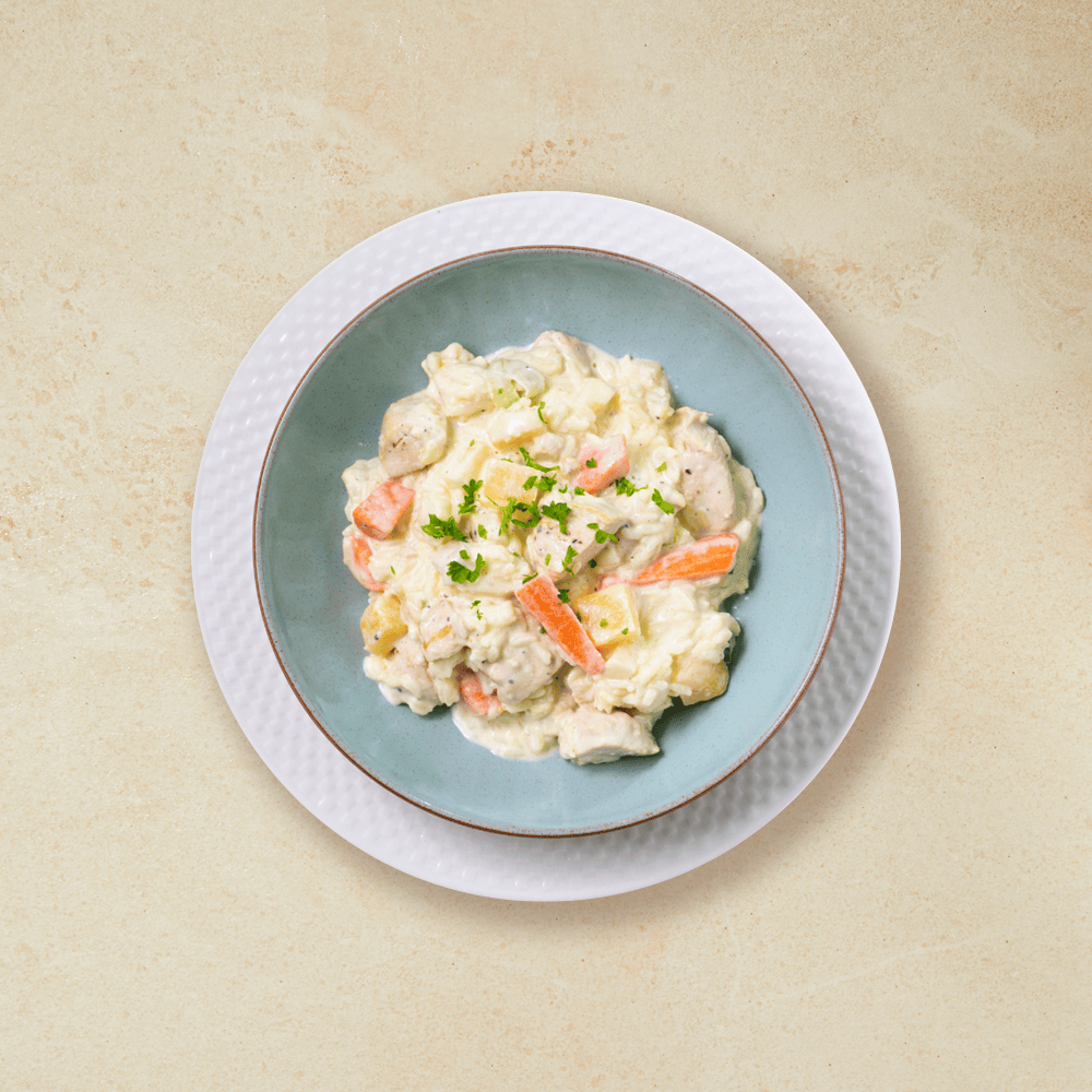 Kyllinggryte med ris i en tyrkis skål, som står på en hvit tallerken