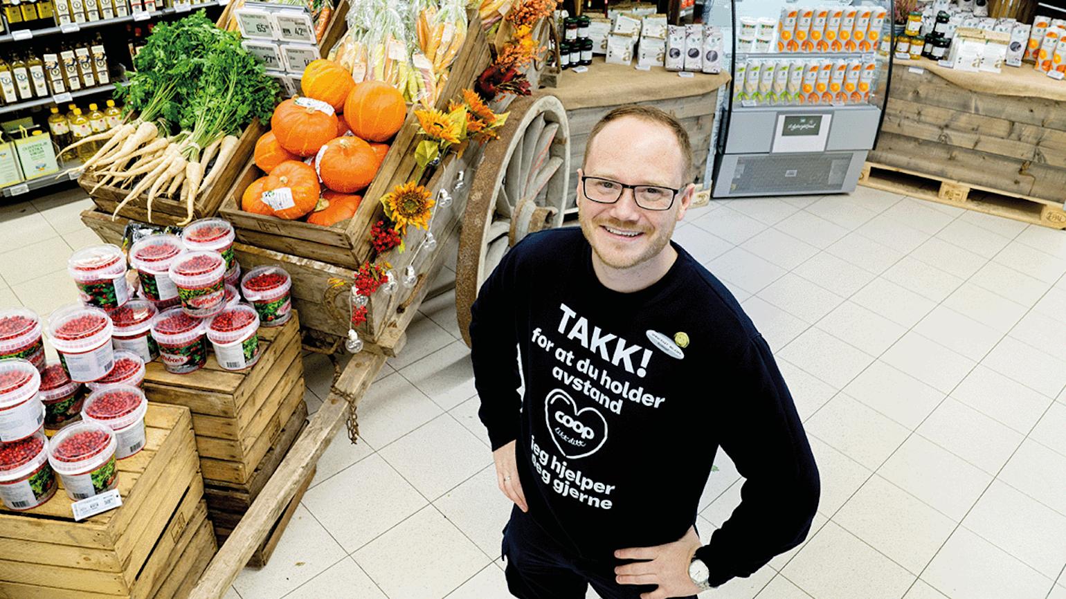 Mann titter smilende opp mot kamera i grønnsaksavdeling.
