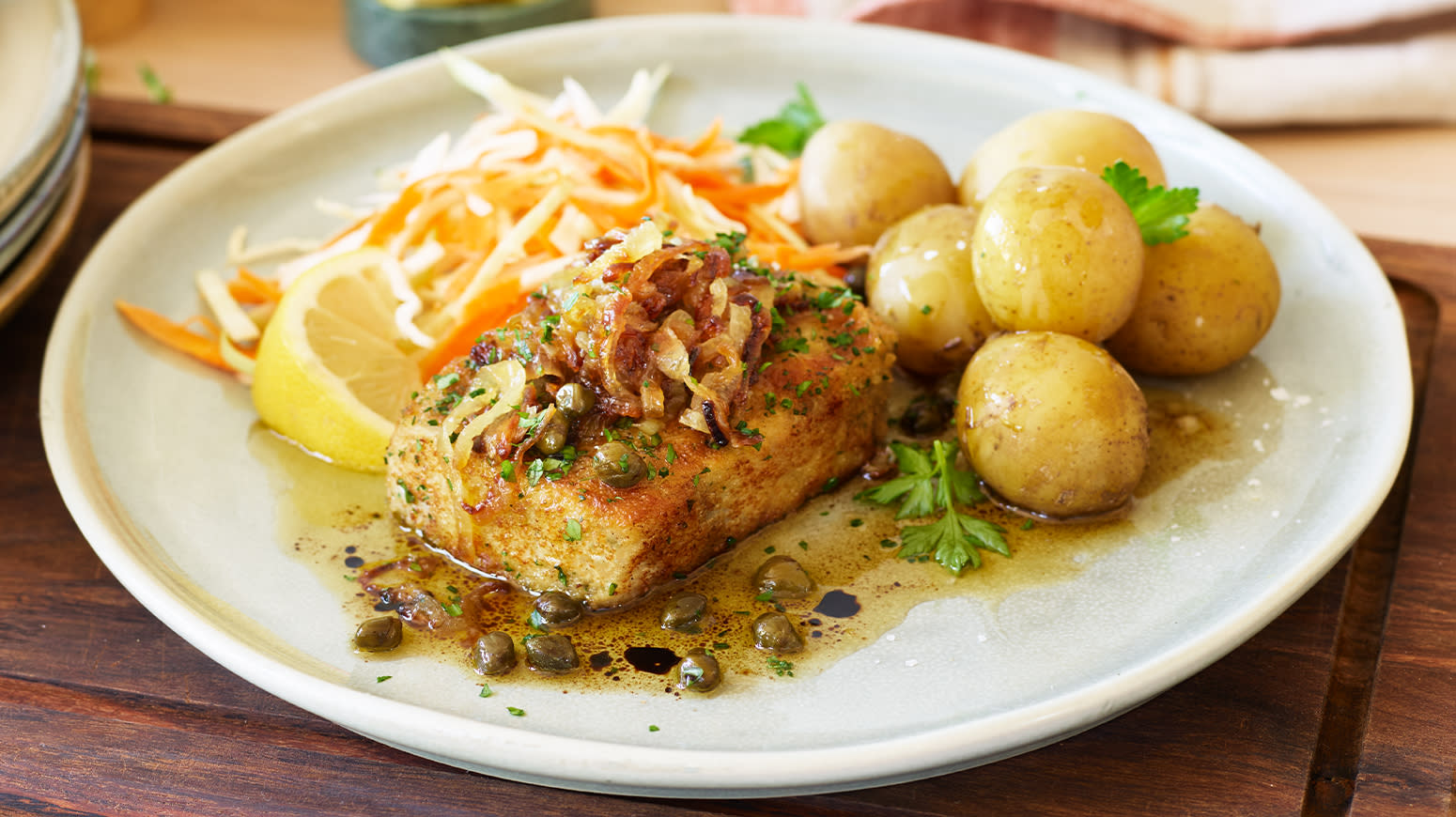 Sprø seibiff med saltkokte poteter, råkost og soyasmør servert på hvit tallerken på mørk trefjøl.