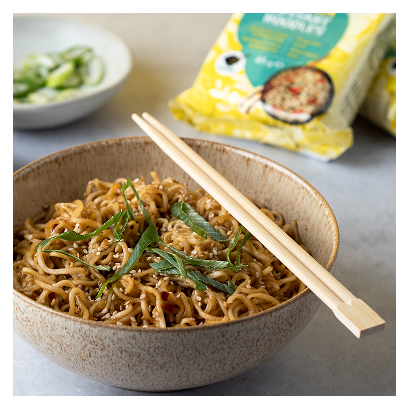 Nudler med sesamfrø og vårløk i en brun skål med spisepinner på