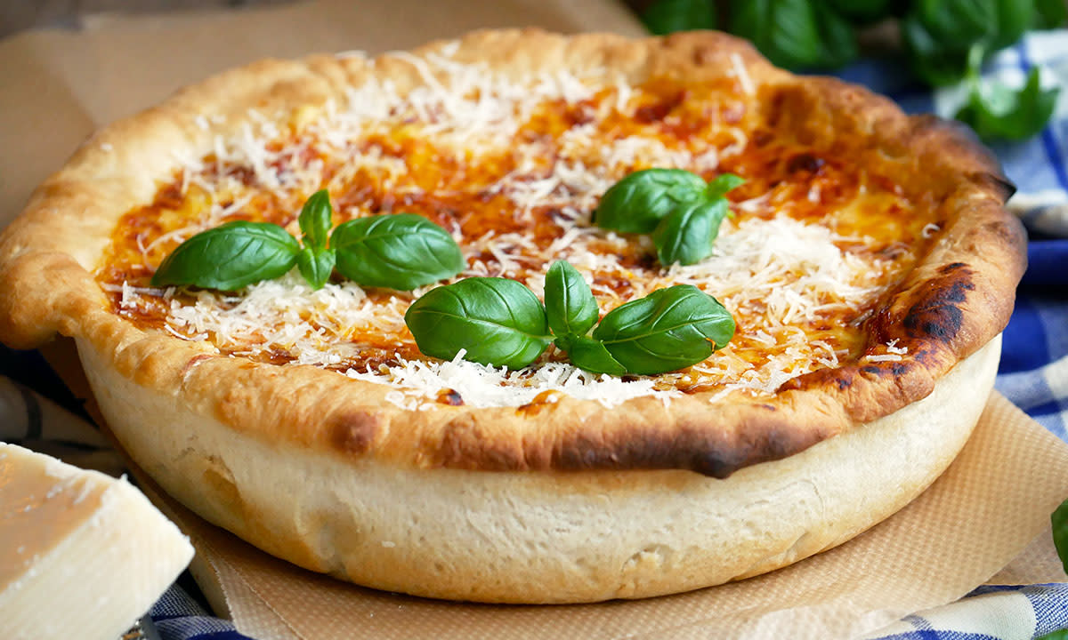 Amerikansk pizza med tykk bunn, toppet med parmesan og basilikumblader