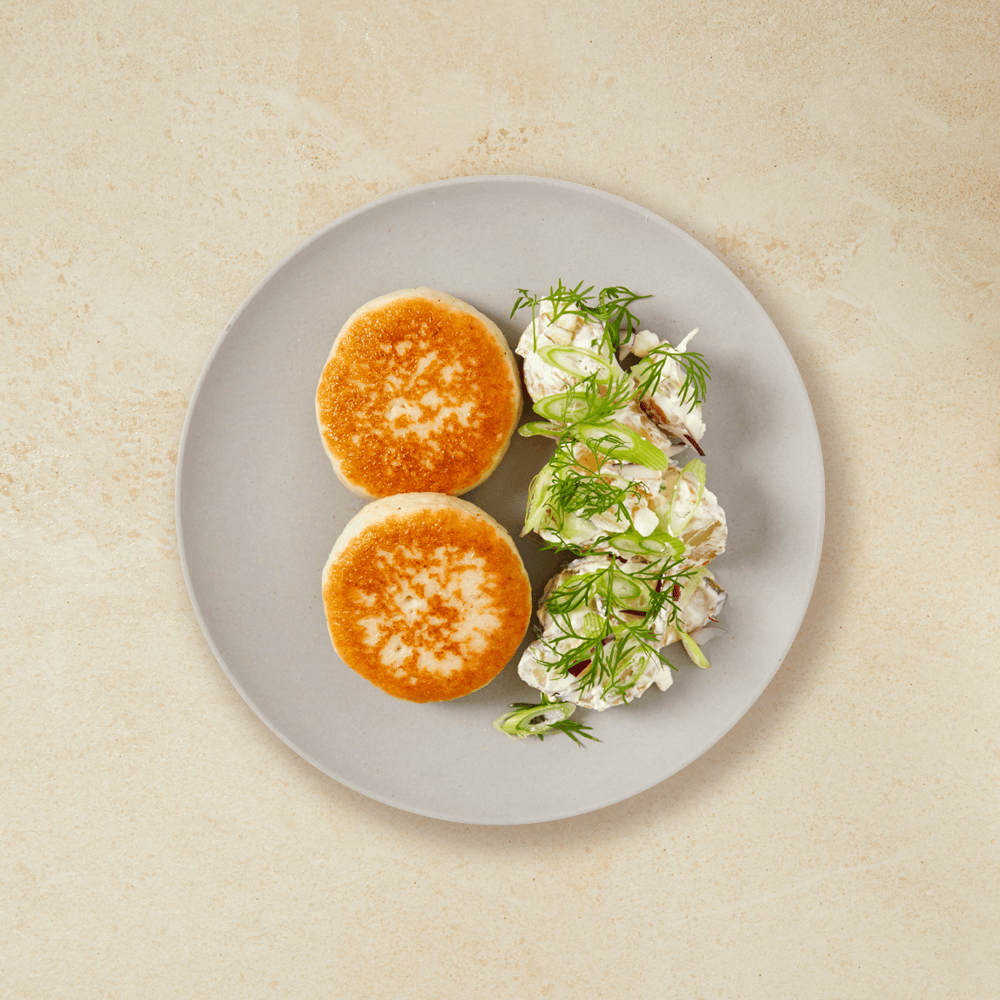 To fiskekaker med kremet potetsalat, ligger på en grå tallerken