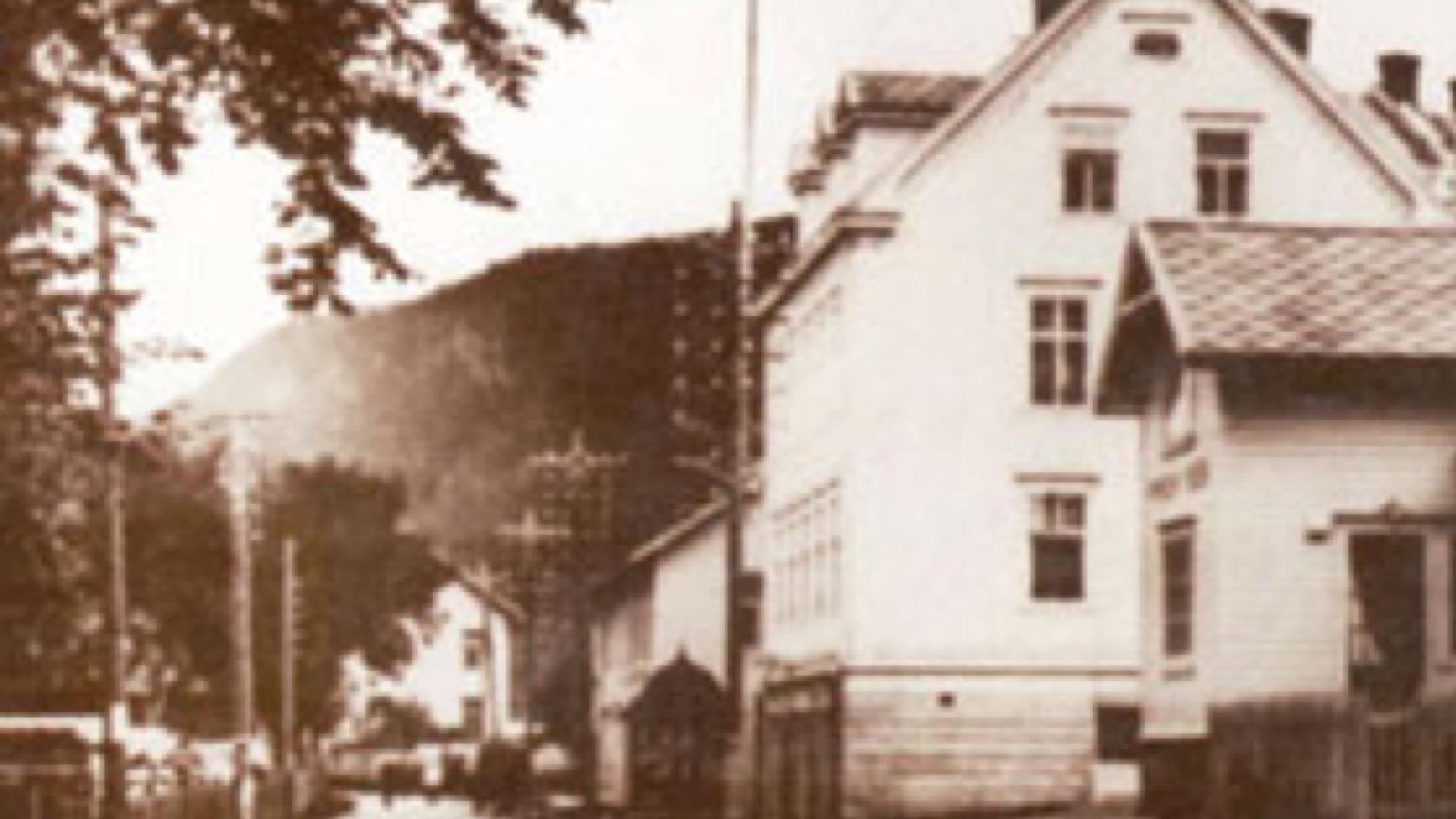 Gammelt brunt bilde av en vei med et hus.