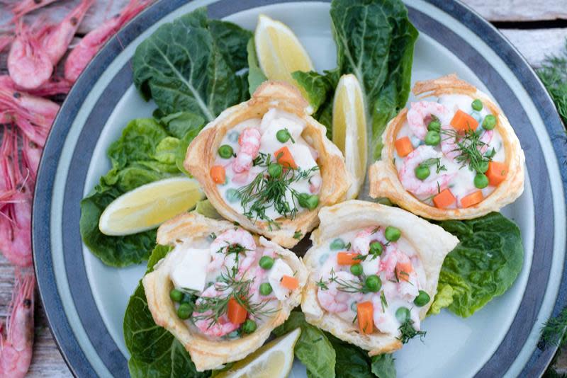 Hjemmelagede terteskjell, med fyll av reker, fiskepudding, erter og gulrot. Servert på blått fat med salatblader, sitron og dill.