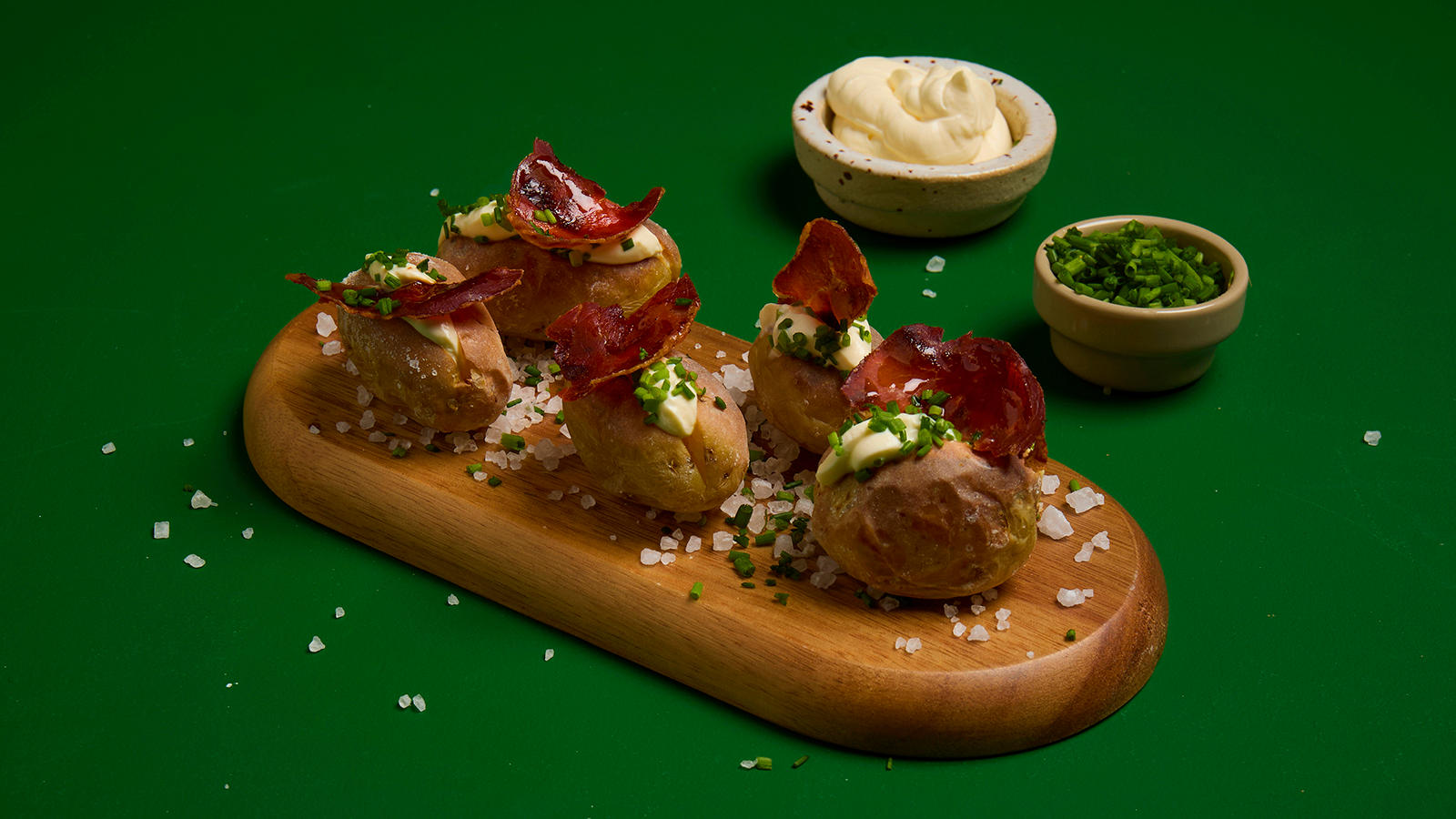 Saltbakte småpoteter med spekeskinke servert med aioli og friske urter på liten trefjøl.