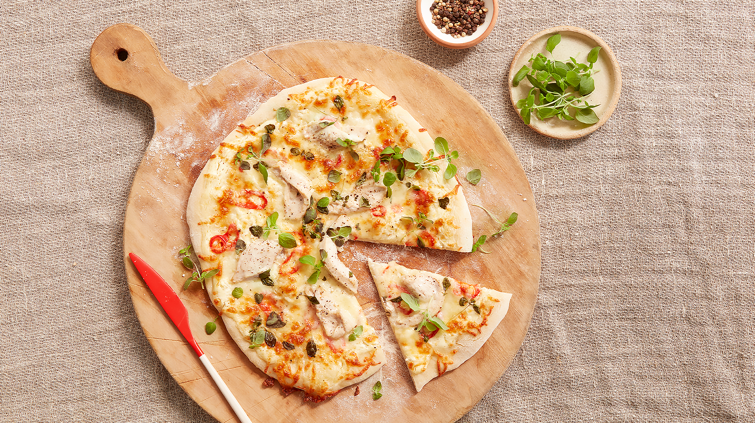 Hvit pizza med crème fraîche og kylling, laget av hjemmelaget pizzadeig. Servért på rund trefjøl.