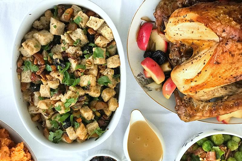 Smakfull og fruktig stuffing til kalkun, servert i oval hvit ildfast form ved siden av en helstekt kalkun.