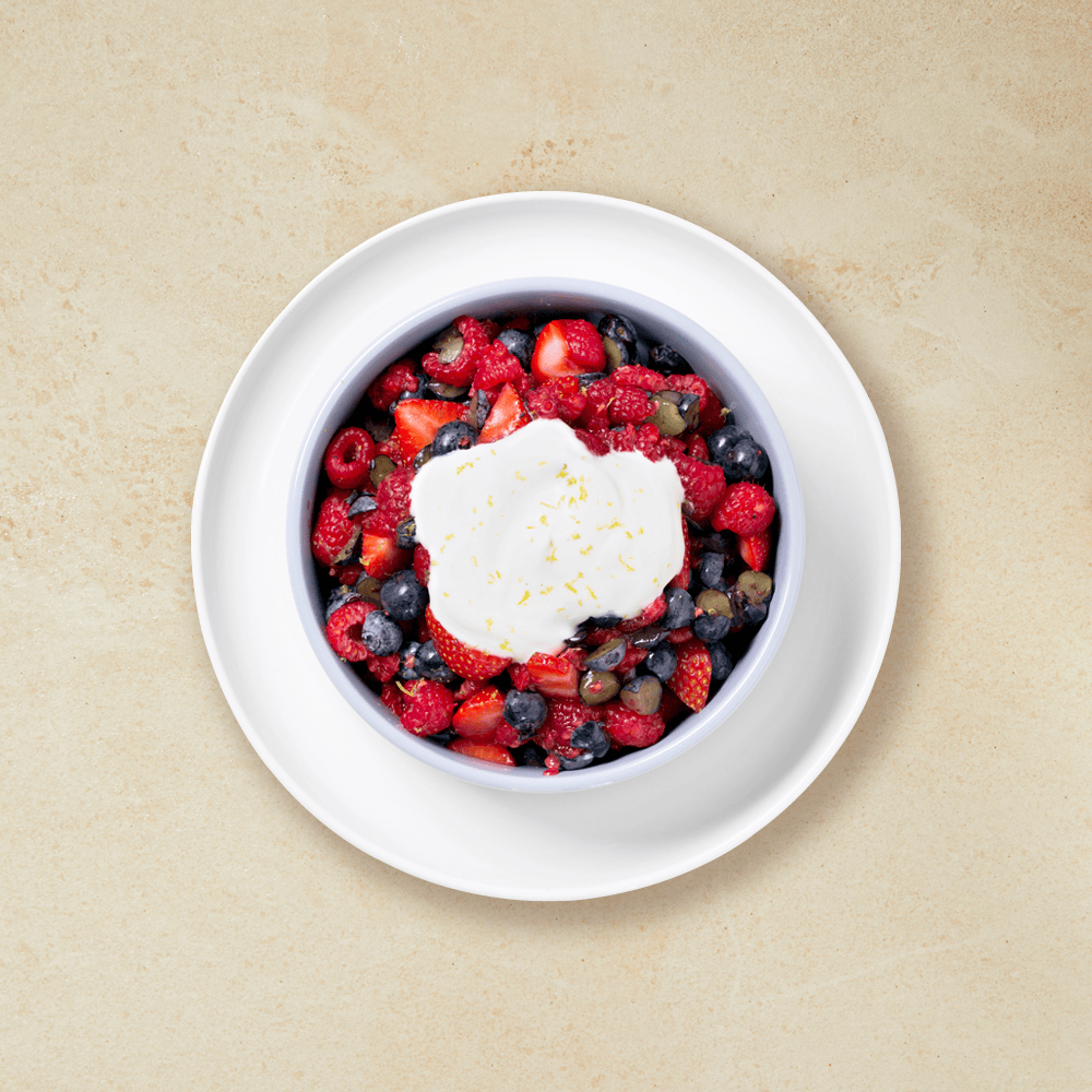 Bærsalsa laget av jordbær, bringebær og blåbær. Servert i hvit skål med yoghurt og limeskall.