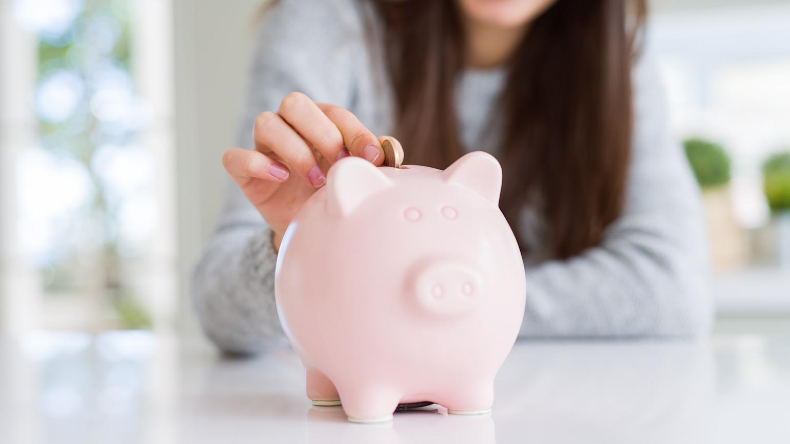 Dame putter penger på en sparegris.