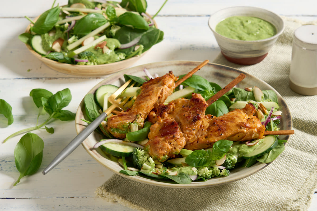 Kyllingsalat med Green Goddess dressing servert i naturfarget skål med grå og gullfarget gaffel. Liten skål med Green Goddess dressing i bakgrunnen.