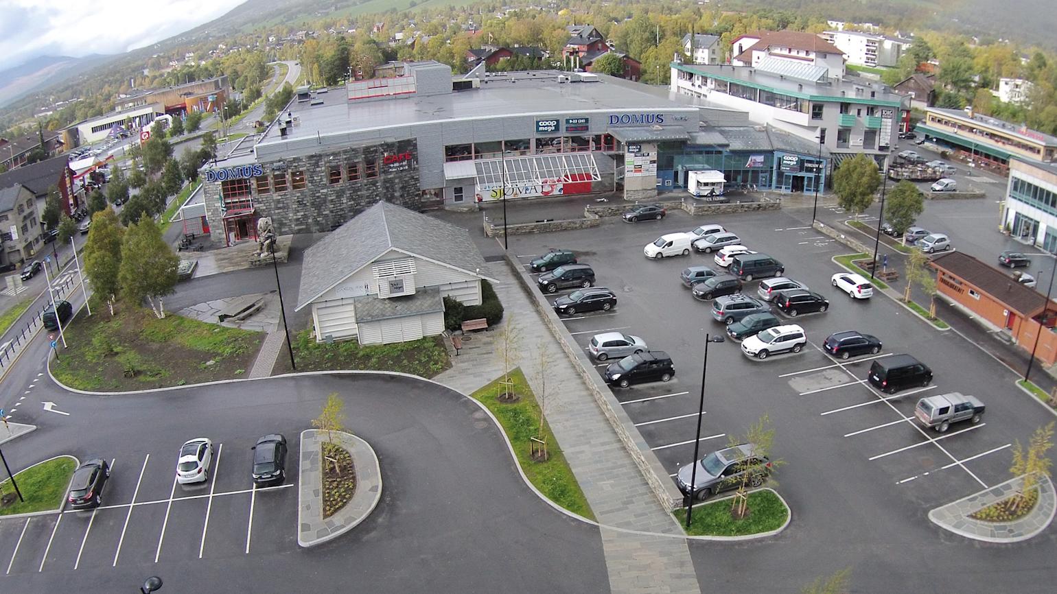 Bildet viser en parkeringsplass og et bygg hos Coop Oppdal SA, som illustrasjon av eiendom til leie.