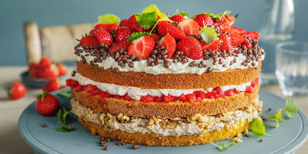 Bløtkake med rørte jordbær og mascarponekrem i tre forskjellige varianter, servert på lyseblått fat med friske jordbær, valnøtter, daimkuler og sitronmelisse.