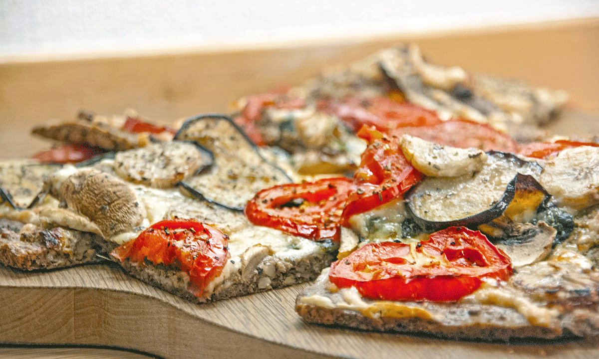 Lavkarbo pizza med nøtter skåret opp på fjøl