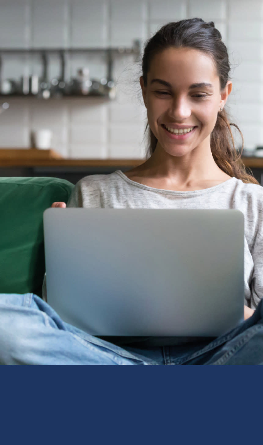 Dame sitter foran dataen og smiler.