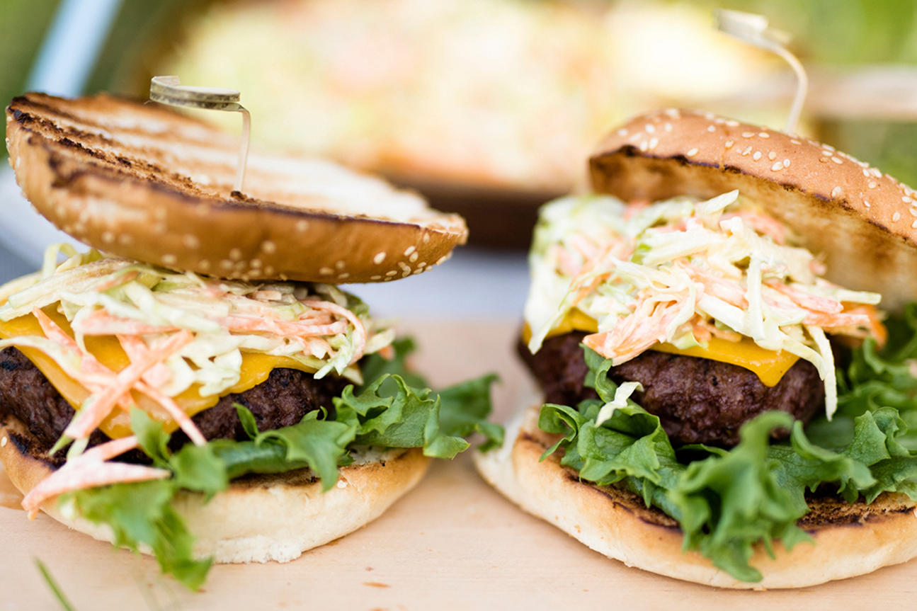 Hjemmelaget coleslaw servert på hjemmelaget hamburger med salat, ost og grillet burgerbrød.