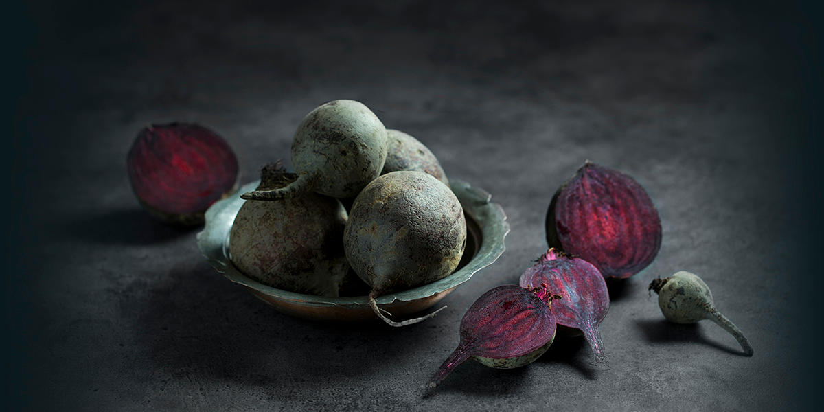 Skål med rå, uskrelte rødbeter. Ved siden av ligger rå rødbeter delt i to.