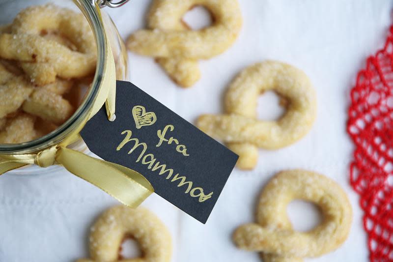 Hjemmelagede berlinerkranser til jul, lagt på glass med gavelapp knyttet på med gavebånd.