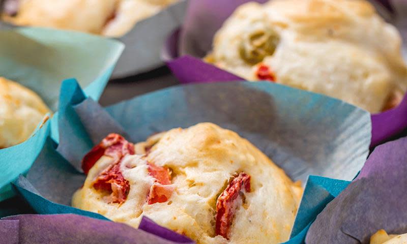 Nærbilde av halvgrove matpakkemuffins med ost, skinke og paprika servert i blå og lilla muffinsformer.