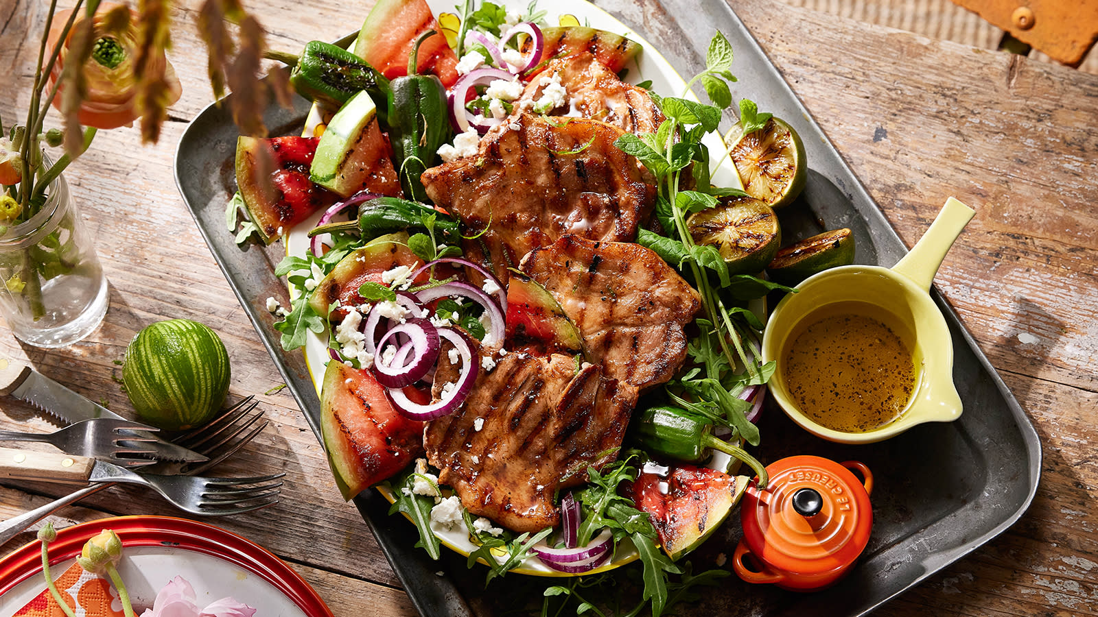 Grillnakke med vannmelonsalat servert på metallfat med fetaost, rødløk og en syrlig dressing.