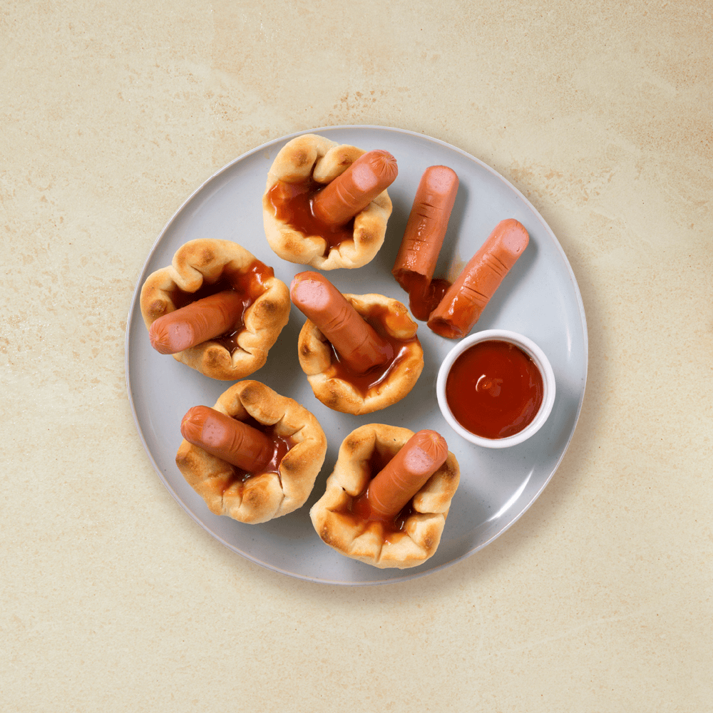 Avkappede pølsefingre til Halloween servert i pizzakurver med ketsjup på grå tallerken. Liten skål med ketchup på siden.