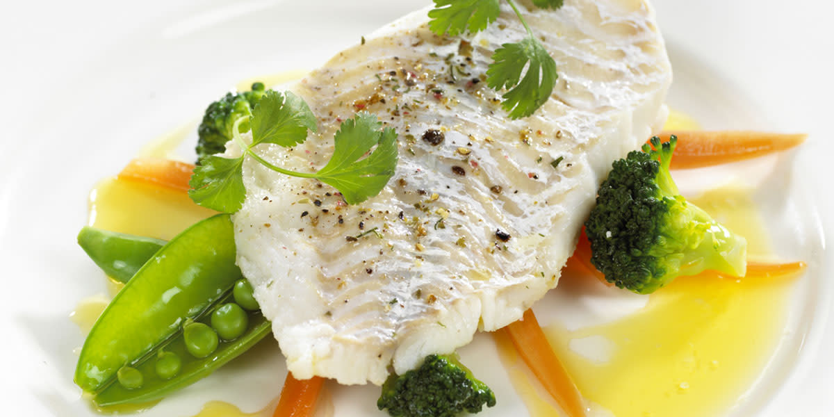 Kokt juletorsk servert på hvit tallerken med grønnsaker, sandefjordsmør og grønne urter på toppen.