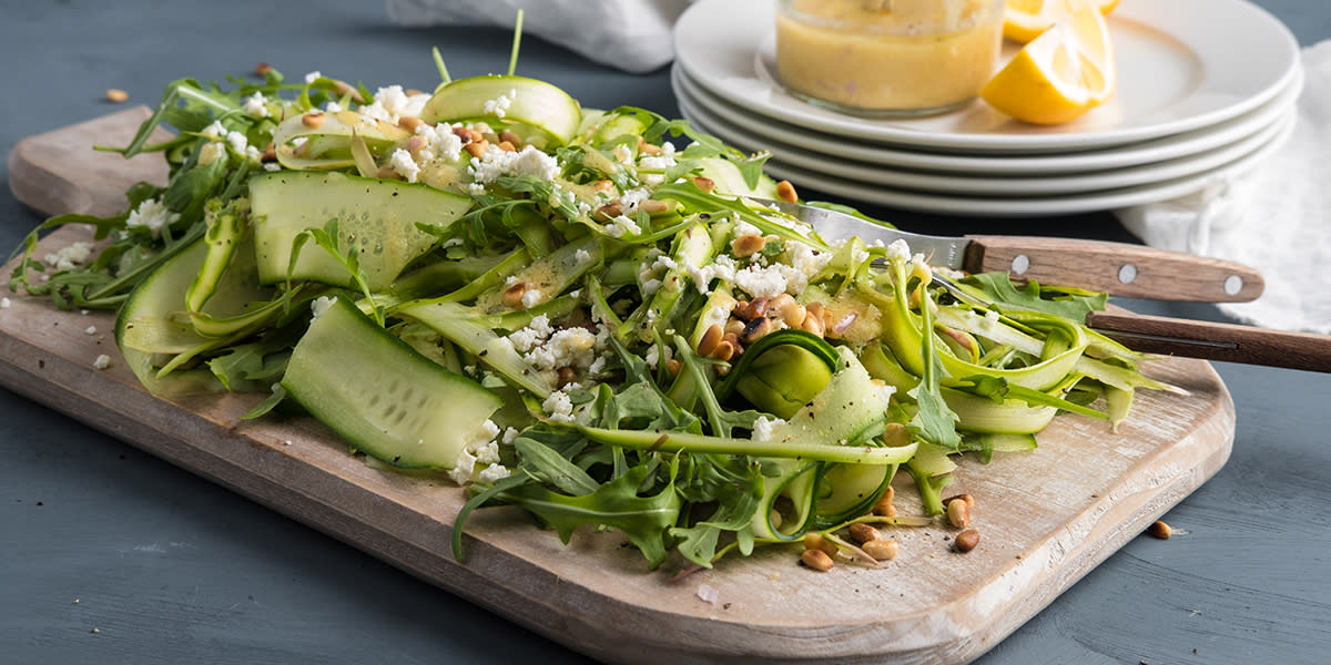 Fjøl med salat med asparges, agurk i brede bånd, ruccola, fetaost og pinjekjerner.